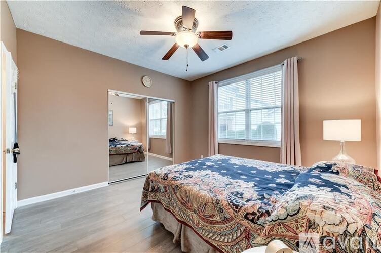 A bedroom with a large bed and a ceiling fan.