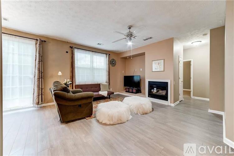 A living room with a brown couch, a white rug, and a fireplace.