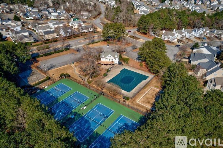 An aerial view of a tennis court surrounded by trees and a swimming pool.