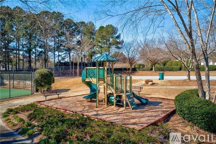 A playground with a green slide and a wooden swing set.