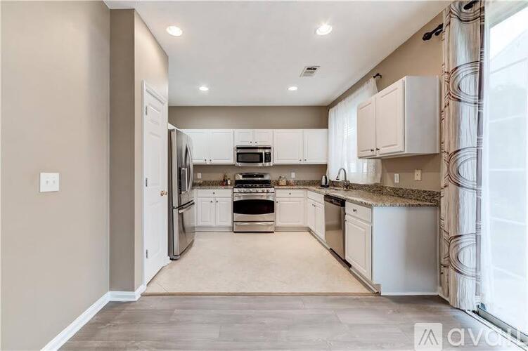 A kitchen with white cabinets and appliances, and a beige wall.
