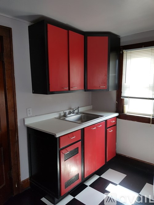 A kitchen with red cabinets and a black and white checkered floor.