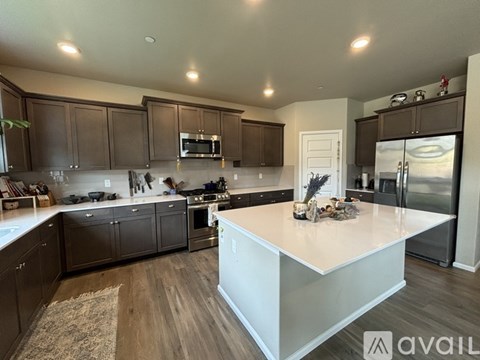 A modern kitchen with dark brown cabinets and a white island.