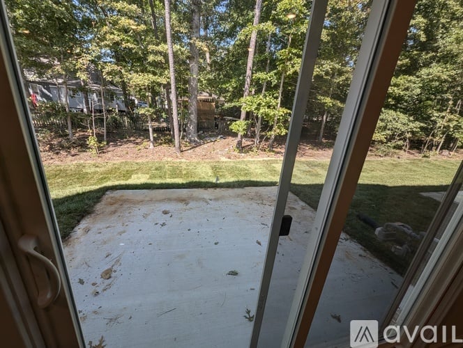 A view from a window looking out to a yard with a dirt path and trees.