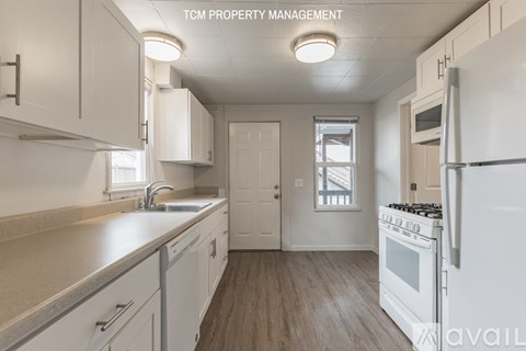 A kitchen with white cabinets and a white refrigerator.