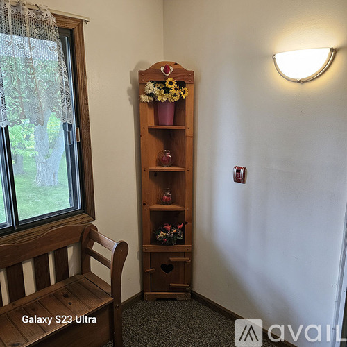 A wooden bench sits next to a tall wooden shelf with flowers on it.