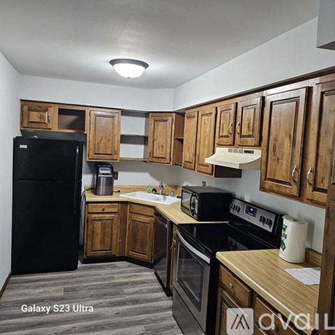 A kitchen with wooden cabinets and black appliances.