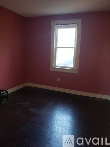 A room with a window and a black box on the floor.