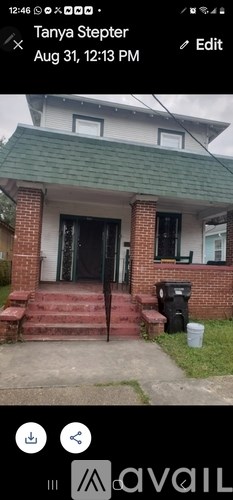 A house with a black door and a brick base is shown.