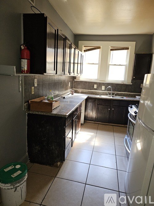 A kitchen with black cabinets and a white refrigerator.