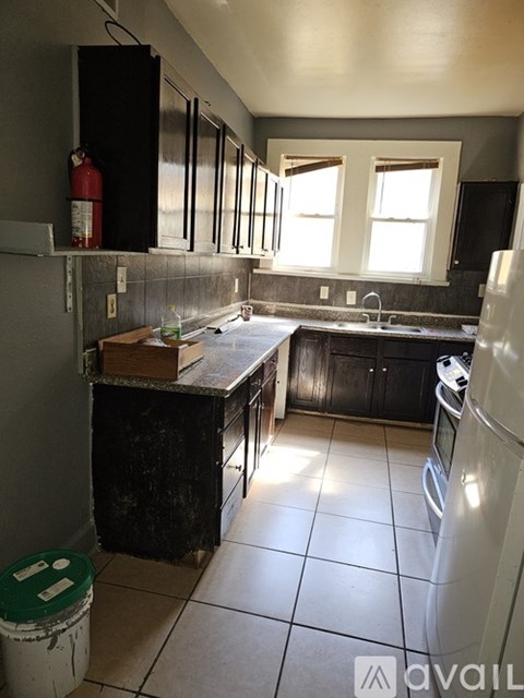 A kitchen with black cabinets and a white refrigerator.