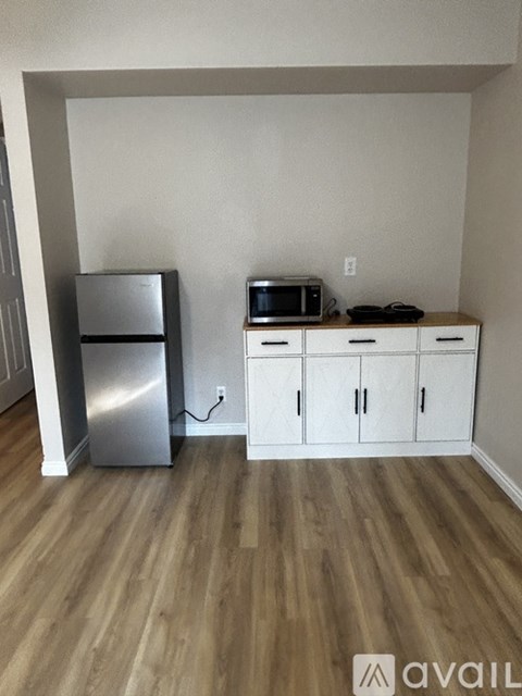 A kitchen with a refrigerator, microwave, and cabinets.