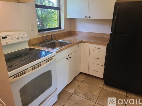 A kitchen with white cabinets and a black refrigerator.