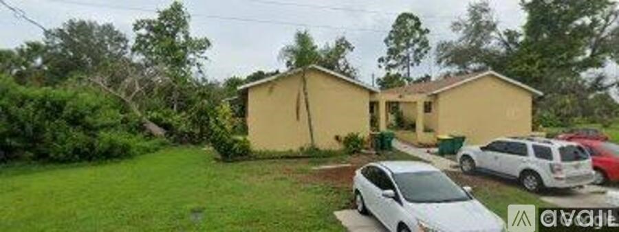 A yellow house with a white car parked in front.