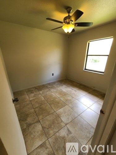 A room with a ceiling fan and tile flooring.