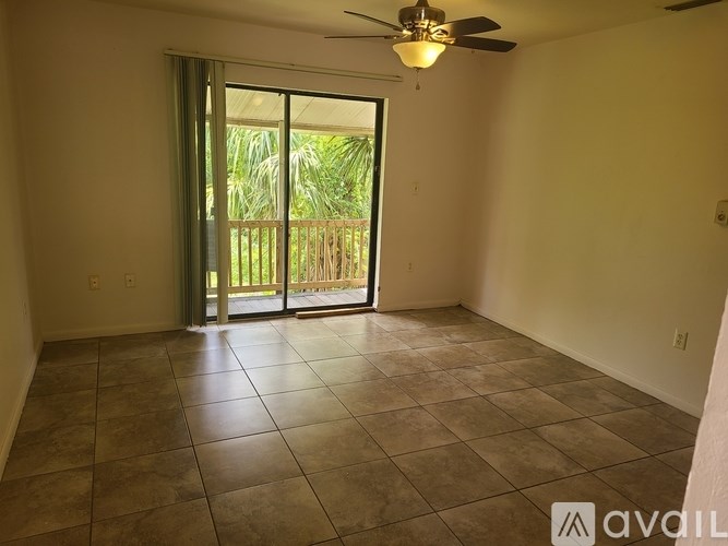 A room with a ceiling fan and sliding glass doors leading to a balcony.