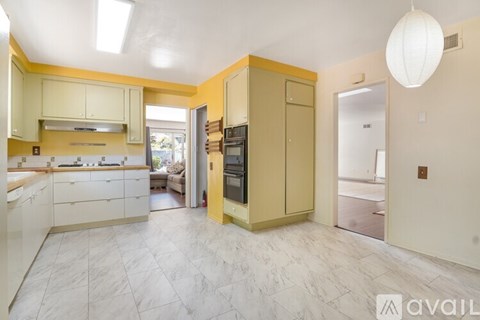 A kitchen with yellow cabinets and a refrigerator.