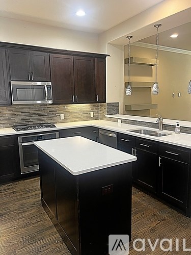 A kitchen with black cabinets and a white island.
