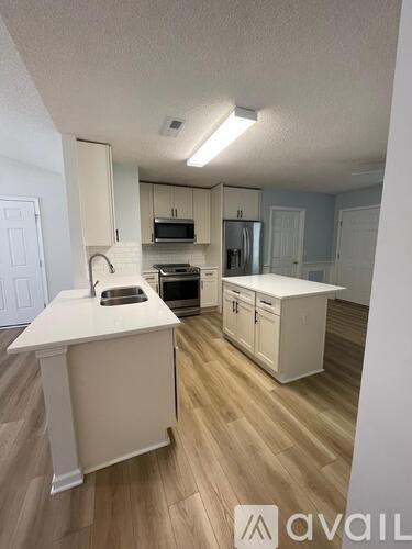 A kitchen with white cabinets and a white island.