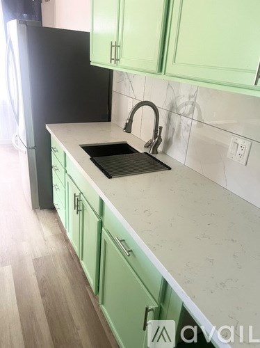 A kitchen with green cabinets and a white countertop.