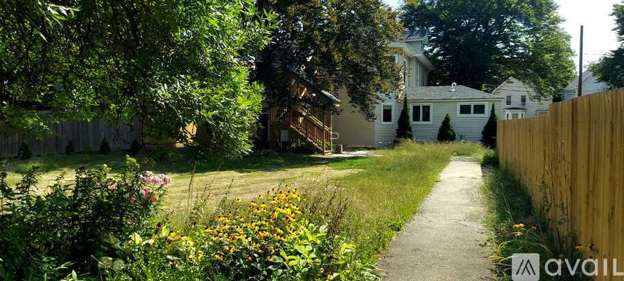 A pathway leads through a grassy area with a wooden fence on the right.