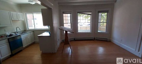 A kitchen with white cabinets and a wooden floor.