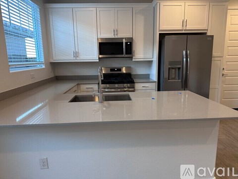 A kitchen with white cabinets and a stainless steel refrigerator.