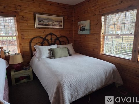 A bedroom with a bed, nightstand, and window.