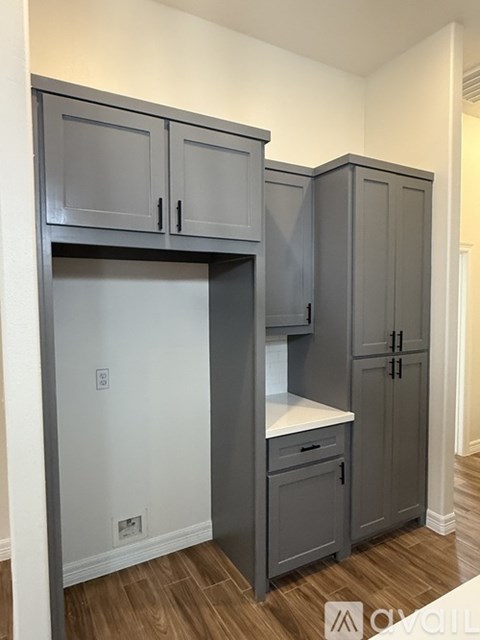 A kitchen with grey cabinets and a white countertop.