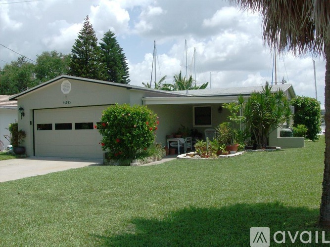 A house with a garage and a tree in front.