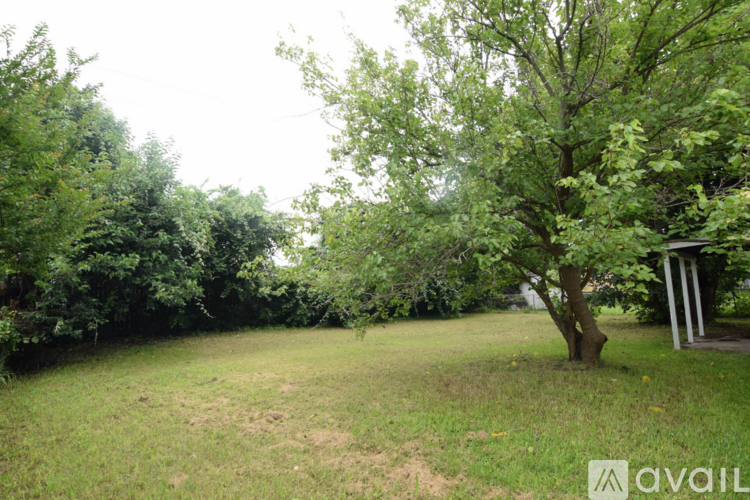 A grassy area with trees and a gazebo in the background.