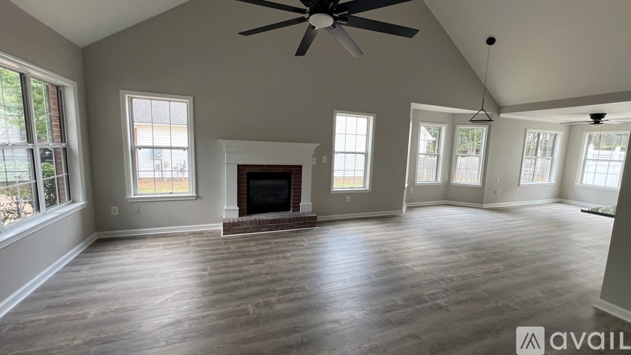 A spacious room with a fireplace and a ceiling fan.