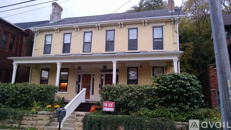 A yellow house with a "For Rent" sign in front.