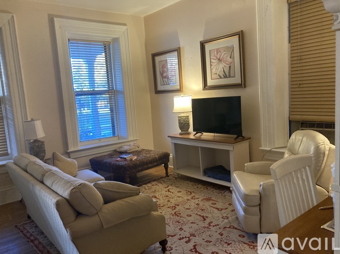 A living room with a white sofa, a white chair, a television, and a coffee table.