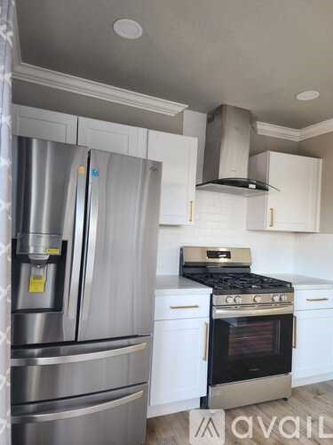 A kitchen with a stainless steel refrigerator and a stainless steel range hood.