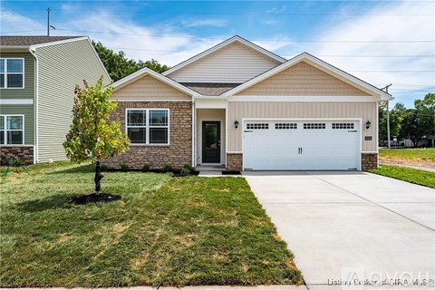 A house with a garage and a tree in front.