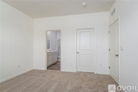 A white bedroom with a carpeted floor and a mirror on the wall.