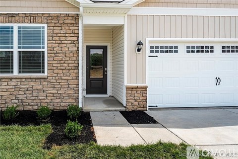 A house with a white garage door and a brown brick wall.