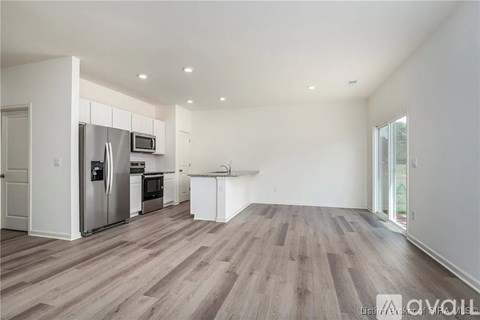 A kitchen with white cabinets and a wooden floor.