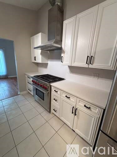 A kitchen with white cabinets and a stove top oven.