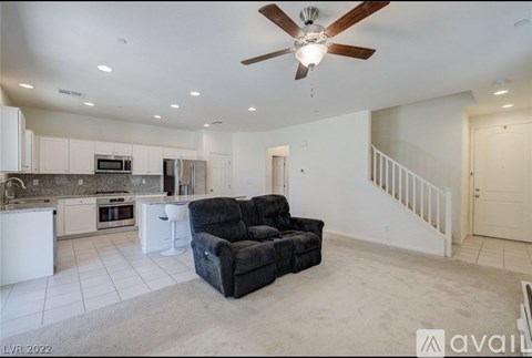 A spacious living room with a black couch and a ceiling fan.