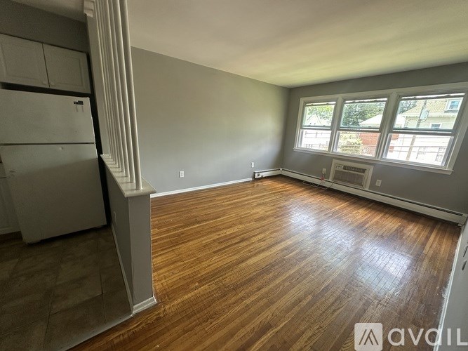 A room with wooden flooring and a window with blinds.