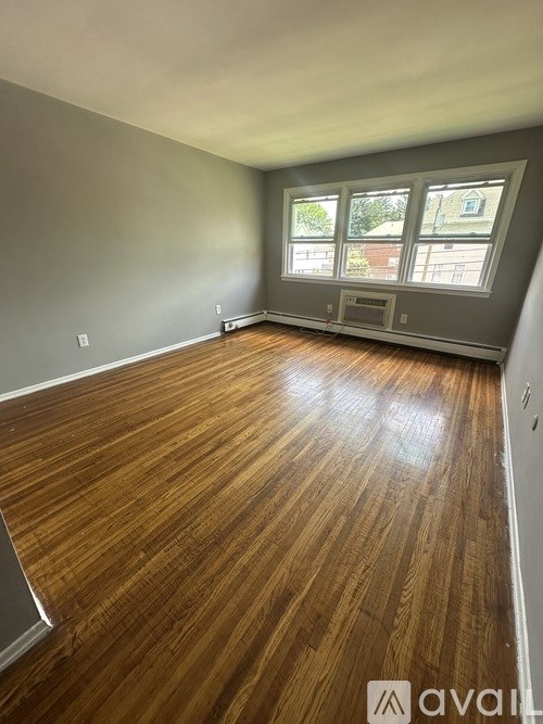 A room with wooden flooring and a window with a view of a building outside.