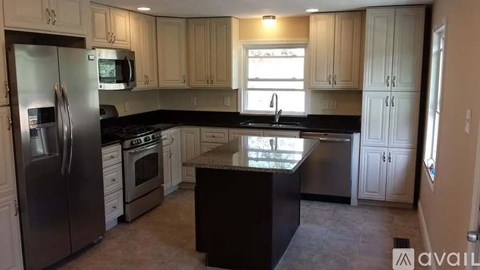 A kitchen with a black countertop and stainless steel appliances.