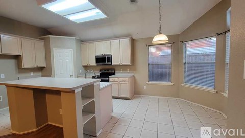 A kitchen with a skylight and a microwave on the counter.