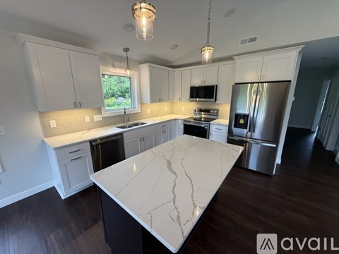 A kitchen with a white marble island and wooden floors.