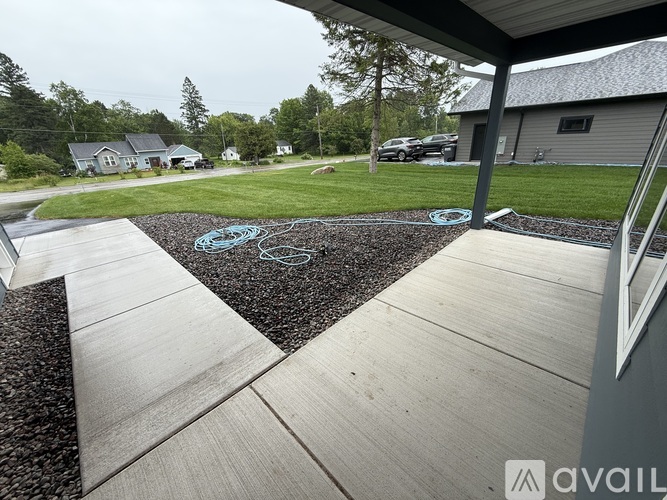A concrete walkway leads to a house with a gravel area in the middle.