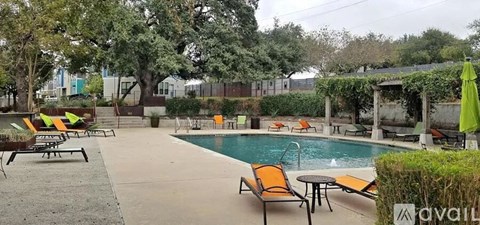 A pool area with orange lounge chairs and a table.