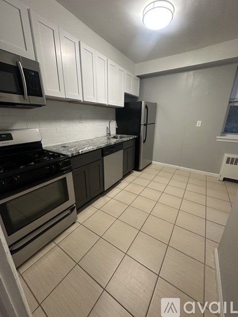 A kitchen with white cabinets and black appliances.