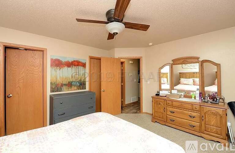 A bedroom with a bed, dresser, and mirror.